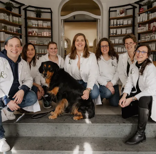 Das Team der Fritz-König-Apotheke sitzt mit einem Hund auf den Stufen in der Offizin